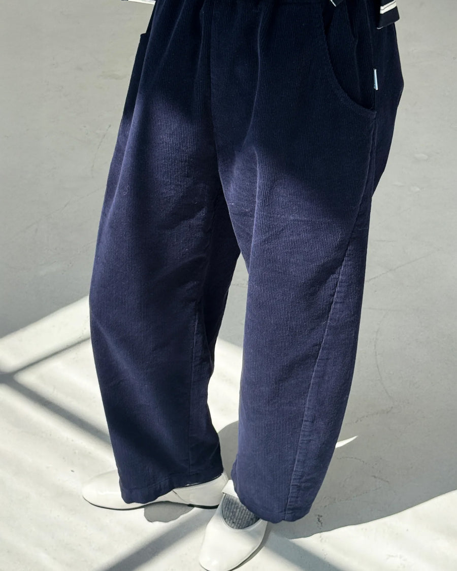 side view of model wearing navy corduroy arc pants with side panels and pockets