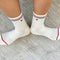 inside of model wearing white socks with red and blue stripe with embroidered red heart