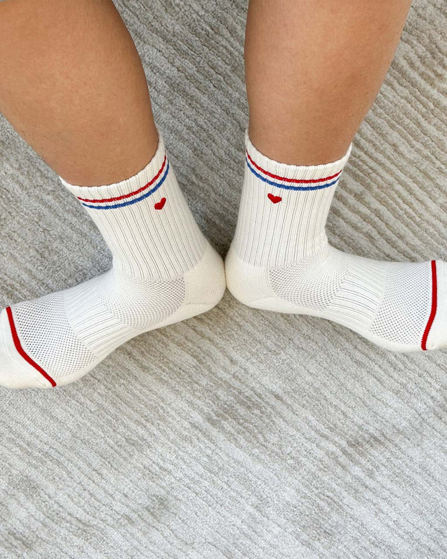 inside of model wearing white socks with red and blue stripe with embroidered red heart