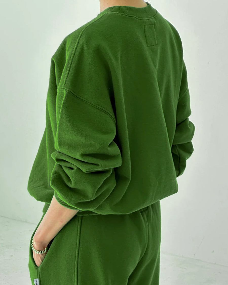 back view of model wearing avocado pull over sweatshirt with slight balloon sleeve and waist band
