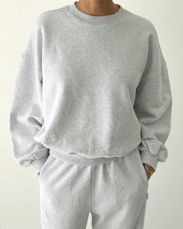 model wearing icy grey pull over sweatshirt with slight balloon sleeve and waist band