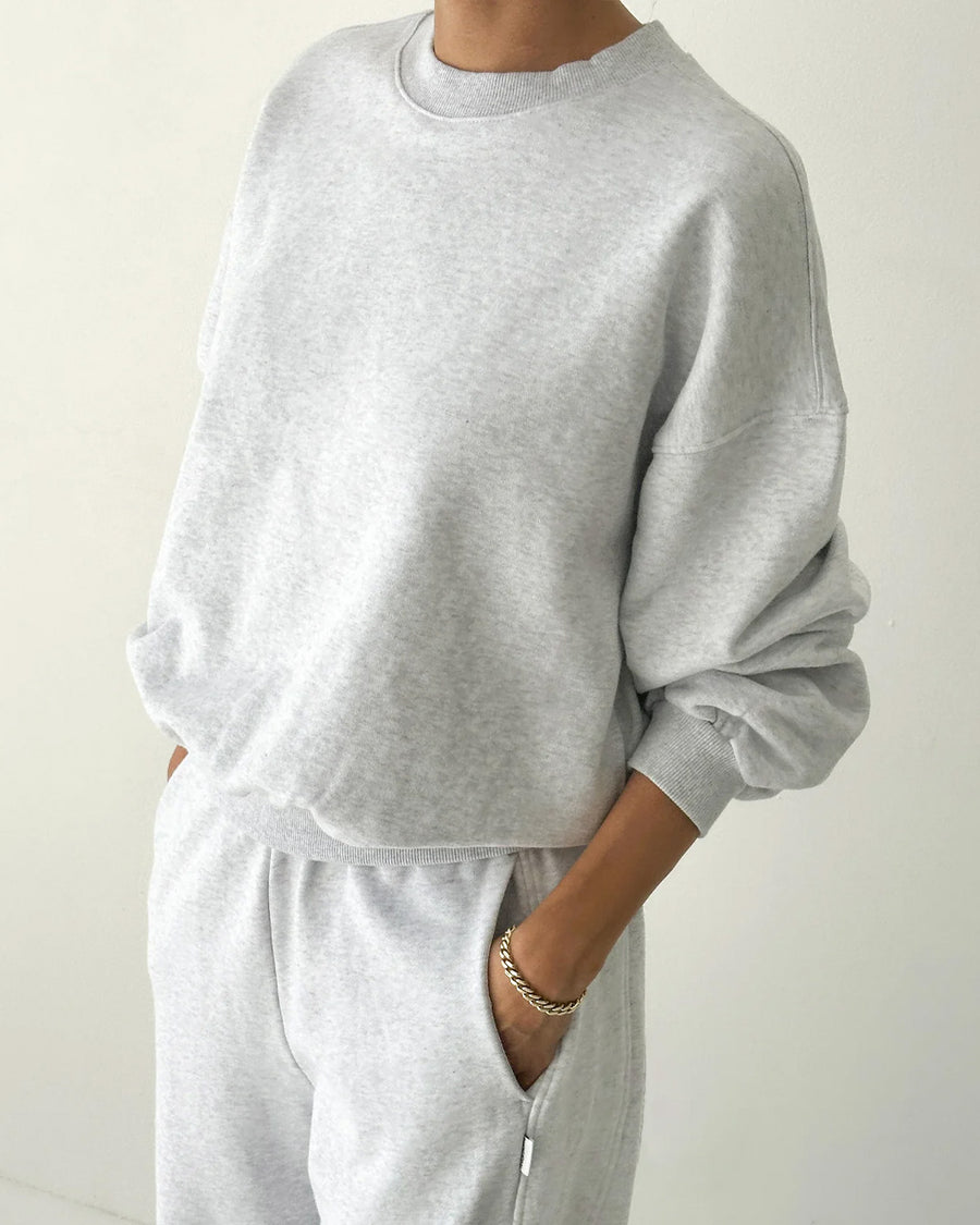 side view of model wearing icy grey pull over sweatshirt with slight balloon sleeve and waist band