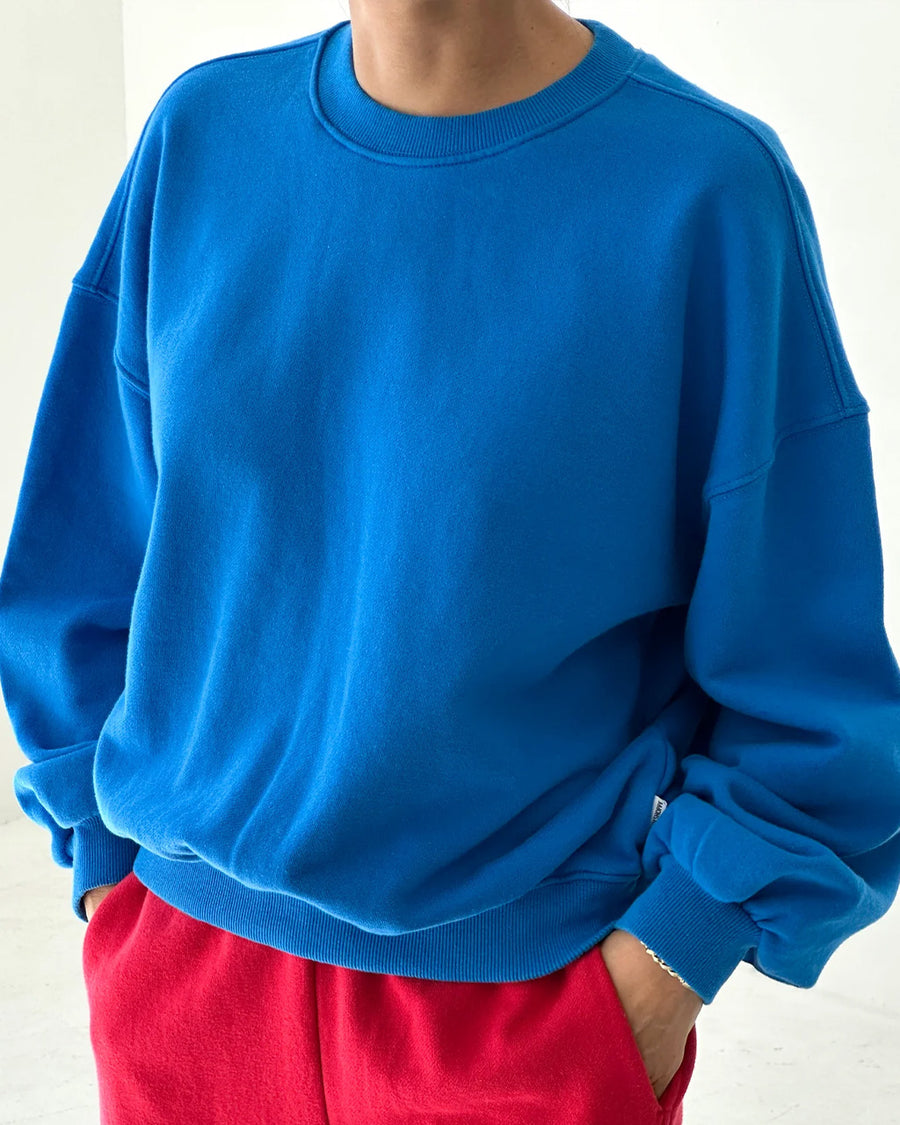 model wearing lagoon blue pull over sweatshirt with slight balloon sleeve and waist band