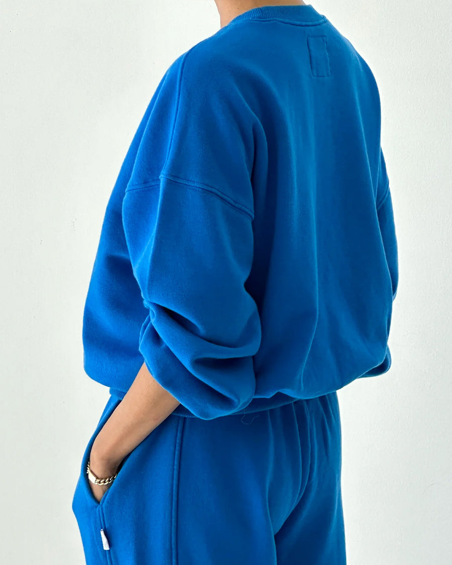 back view of model wearing lagoon blue pull over sweatshirt with slight balloon sleeve and waist band