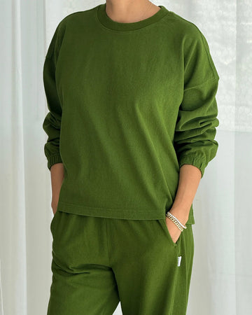model wearing avocado colored long sleeve tee with elastic wristbands