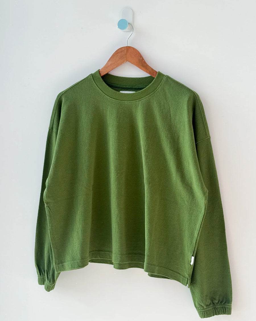 avocado colored long sleeve tee with elastic wristbands on a hanger