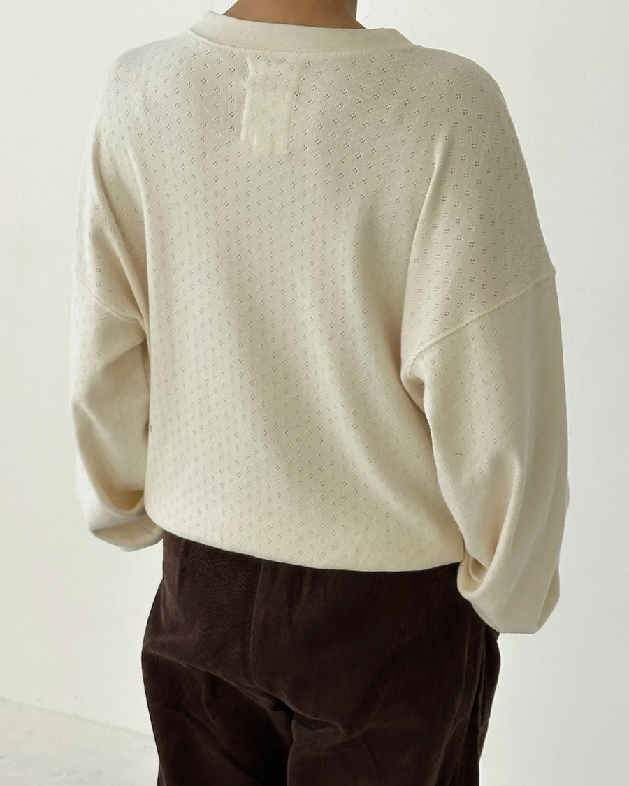 back view of model wearing cream pointelle long sleeve sweatshirt with banded wrists and waist