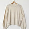 cream pointelle long sleeve sweatshirt with banded wrists and waist on a hanger