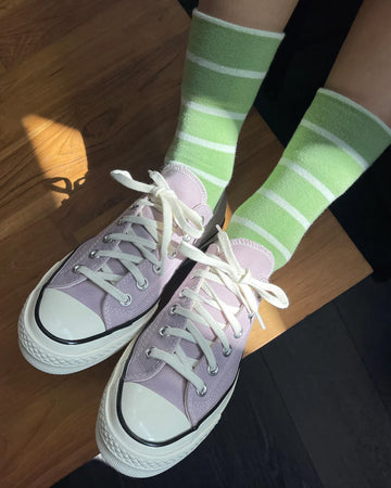 model wearing high green socks with white thin stripes and purple converses