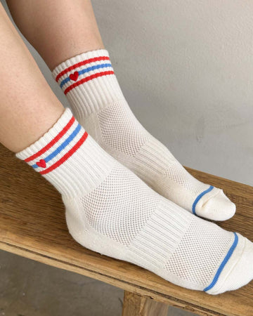 model wearing white socks with red and blue stripes with red embroidered heart detail