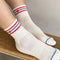 model wearing white socks with red and blue stripes with red embroidered heart detail