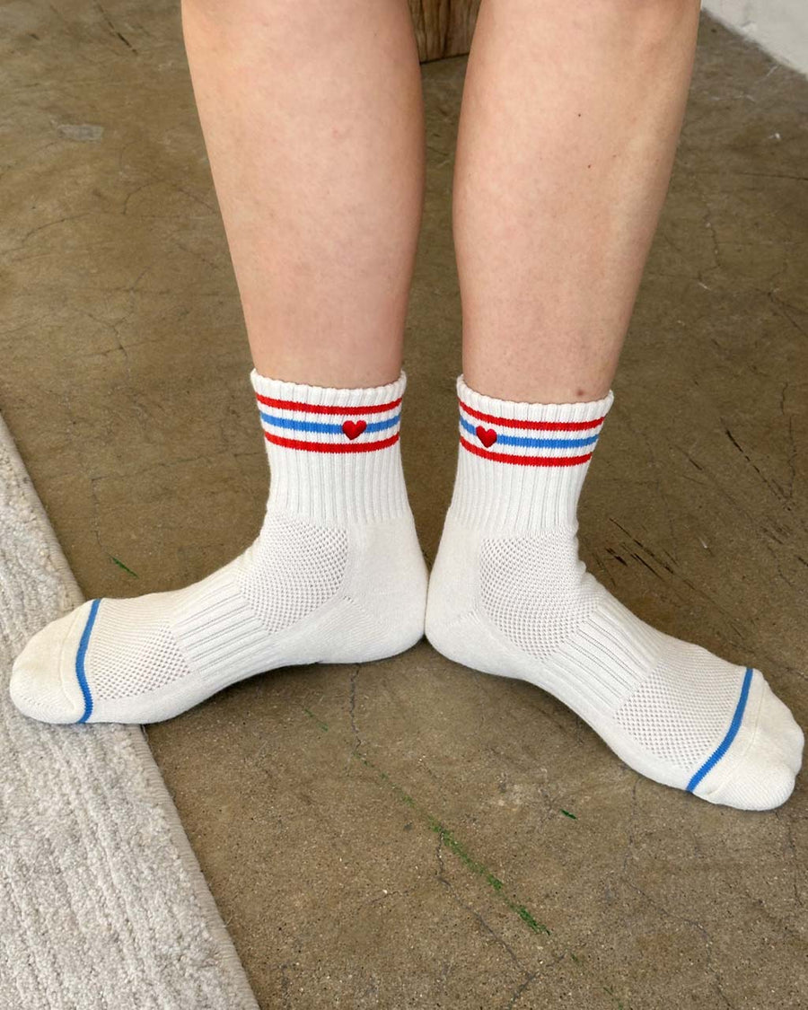inside of model wearing white socks with red and blue stripes with red embroidered heart detail