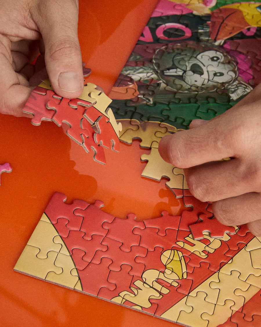 model putting together 500 piece puzzle with realistic colorful retro inflatables piled on each other