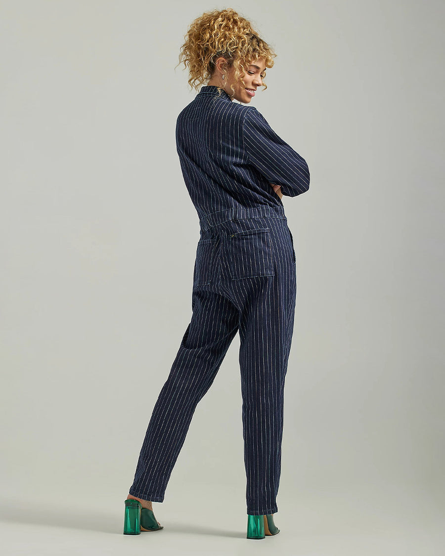 backview of model wearing dark blue denim unionall with multi color vertical stripes