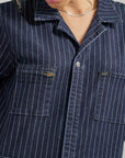 up close of model wearing dark blue denim unionall with multi color vertical stripes
