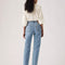 back view of model wearing medium denim slightly relaxed straight leg jeans with cream blouse