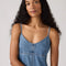 up close of model wearing light denim slip dress with side slits and scalloped lace hem