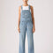 model wearing light denim relaxed fit overalls with front pockets
