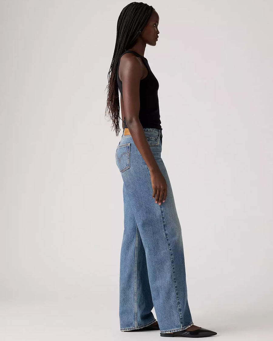 side view of model wearing light denim low loose jeans