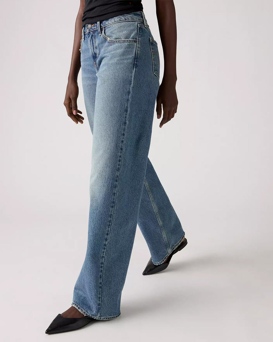 side view of model wearing light denim low loose jeans