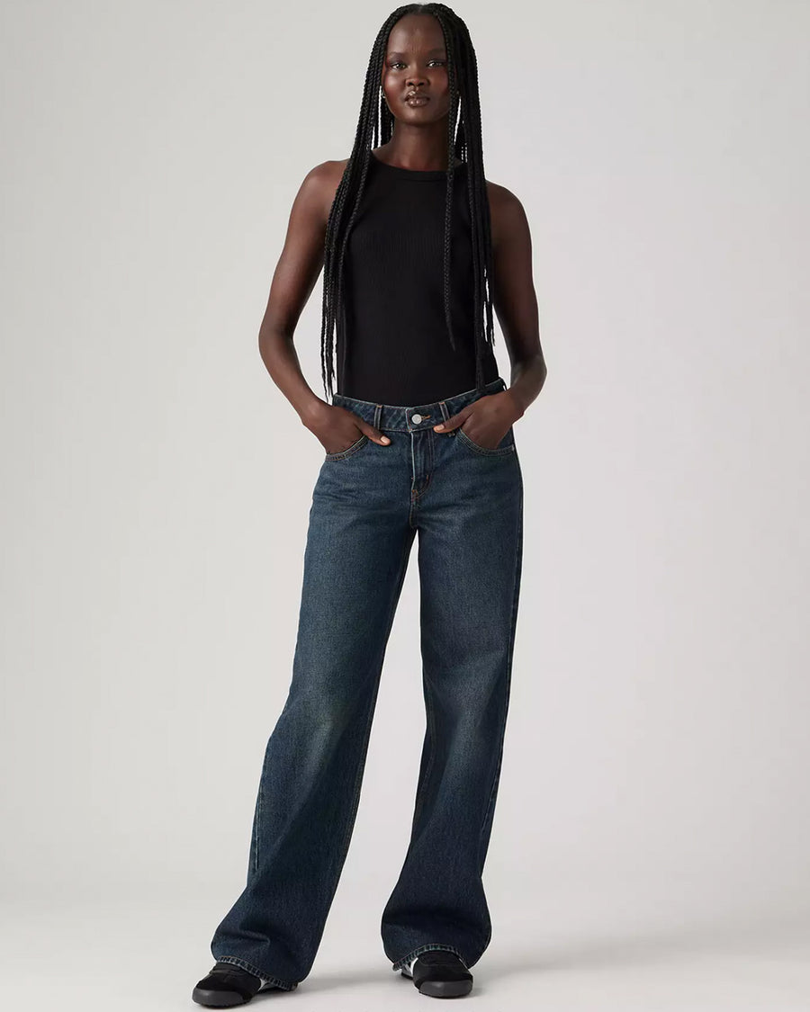 model wearing low rise dark wash denim with a relaxed leg