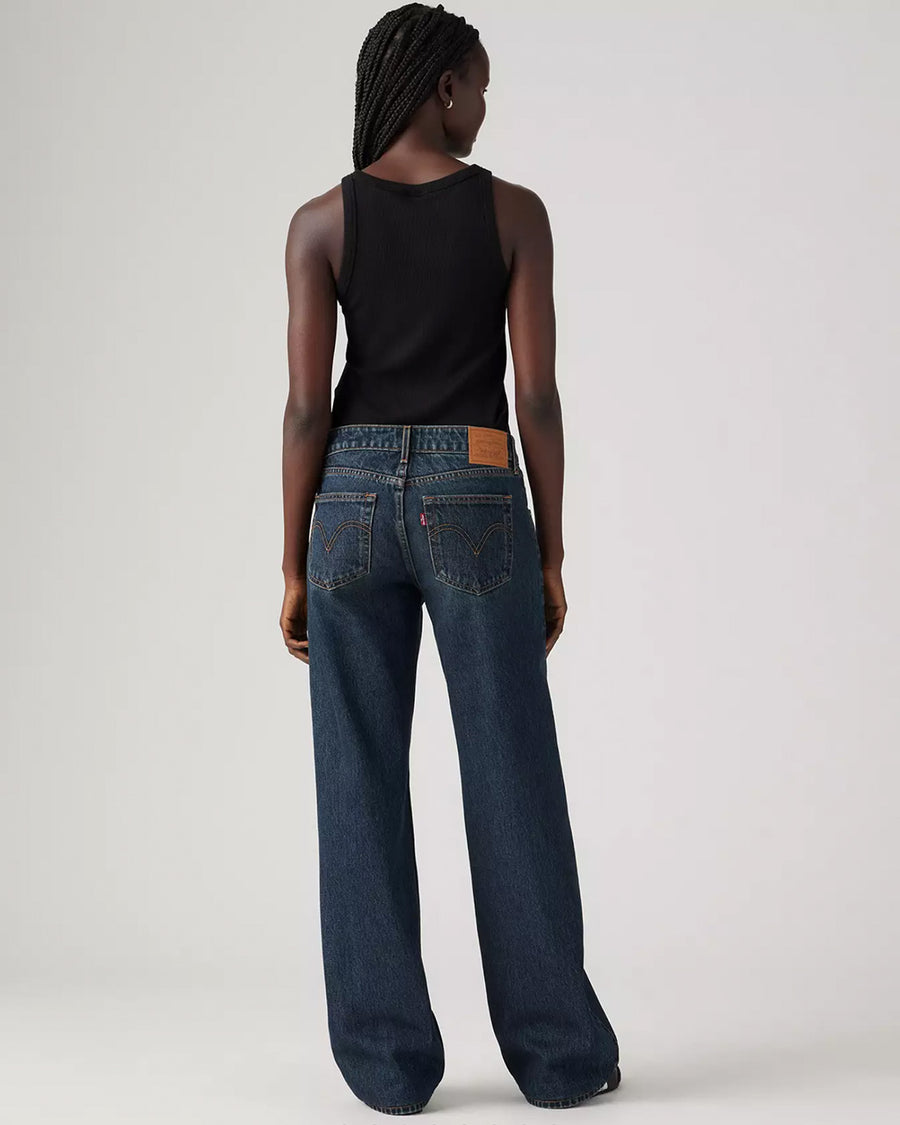 back view of model wearing low rise dark wash denim with a relaxed leg