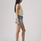side view of model wearing light denim low rise shorts with distressed hem