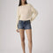model wearing dark denim low rise shorts with frayed hem