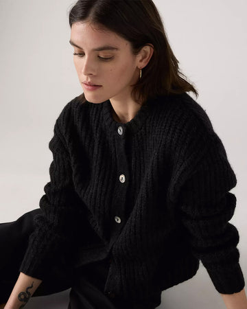 model wearing black textured cardigan with shell buttons