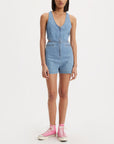 model wearing light denim romper with zip front and cut out sides