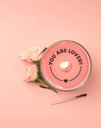 lit candle with message 'you are loved' on the bottom