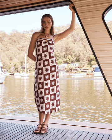model wearing white and brown checkered midi dress with all over sun print