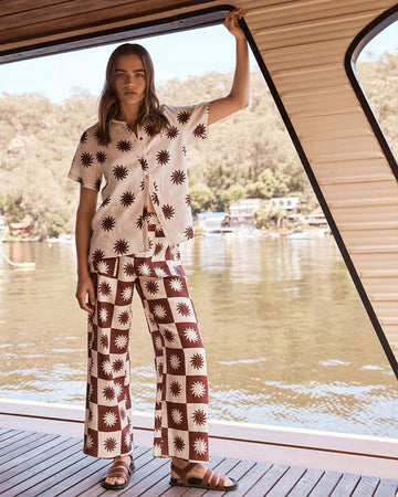 model wearing brown and white linen sun print pants and matching top