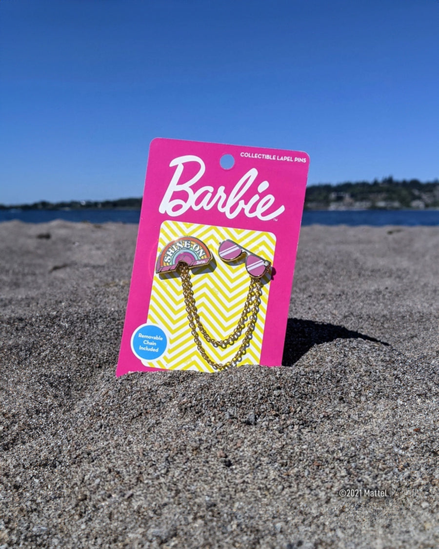 rainbow 'shine on' and pink sunglasses pins with removable double chains on a beach