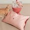 light pink mulberry silk eye mask with embroidered all over cherry print and pink pillowcase with dainty embroidered cherries on the center with an orange cat next to it