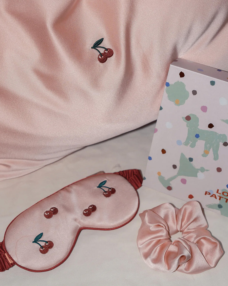 light pink mulberry silk eye mask with embroidered all over cherry print and pink pillowcase with dainty embroidered cherries on the center and pink scrunchie