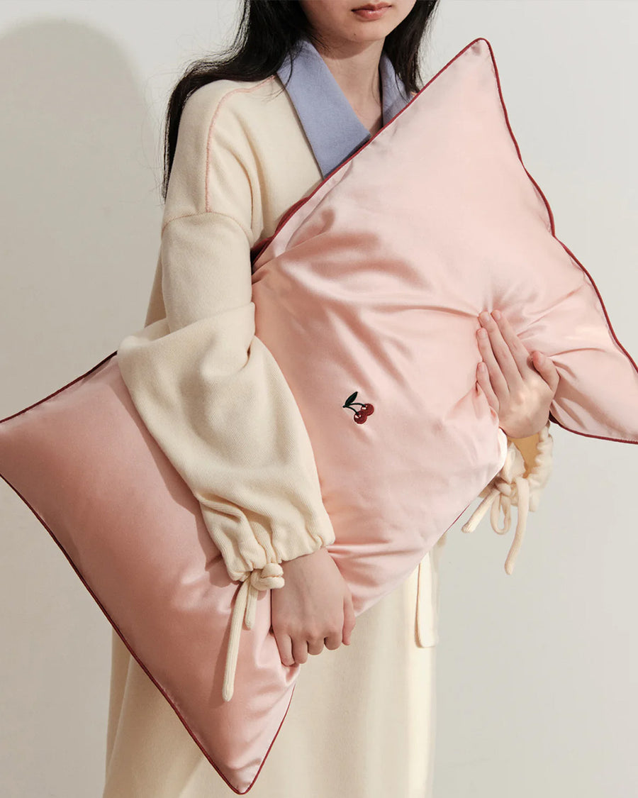 model holding pink mulberry silk pillowcase with embroidered cherries in the center