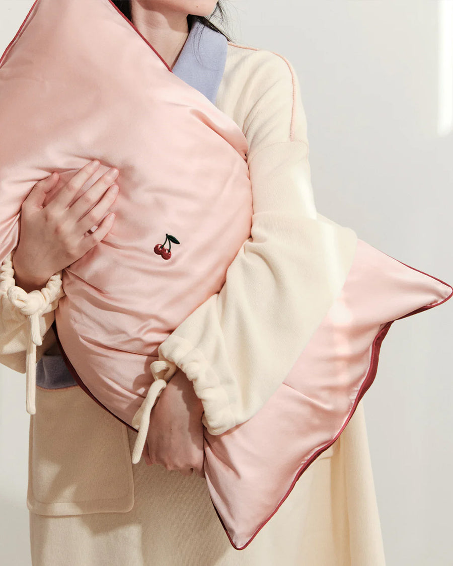 model holding pink mulberry silk pillowcase with  embroidered cherries in the center