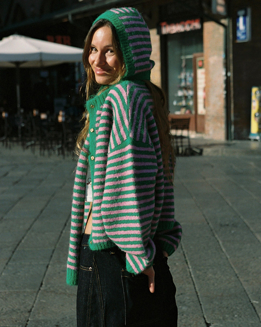 side view of model wearing pink and green thin striped bonnet and matching scarf and sweater