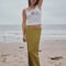 model wearing olive crinkle midi skirt with shaped shell buttons on the top with a white tank