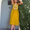 model wearing chartreuse midi dress with white lace accents on the bust, two tie front and ruffle detail on the shoulders