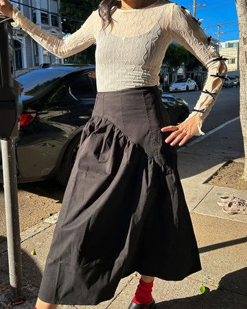 model wearing black twill midi skirt with wavey hem detail