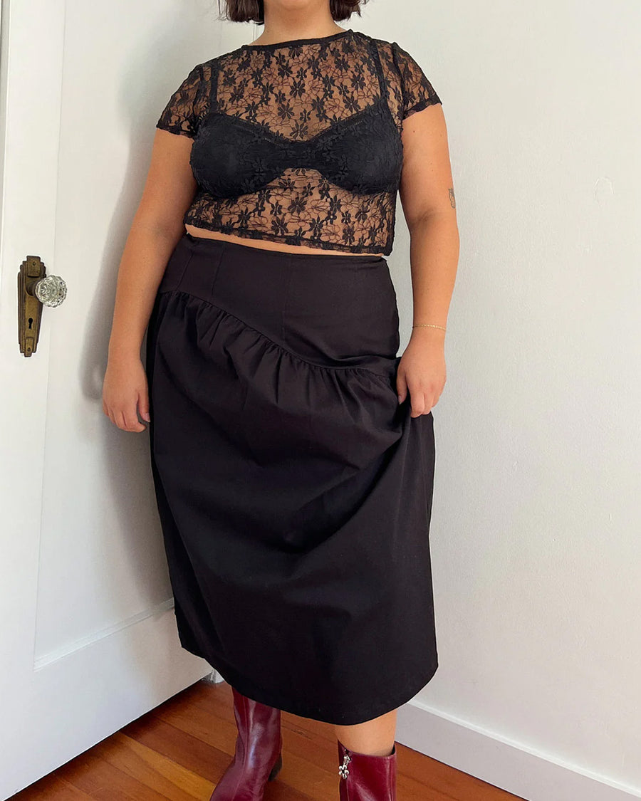 model wearing black twill midi skirt with wavey hem detail