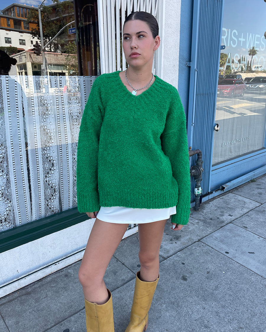 model wearing green textured v-neck sweater and twill skirt