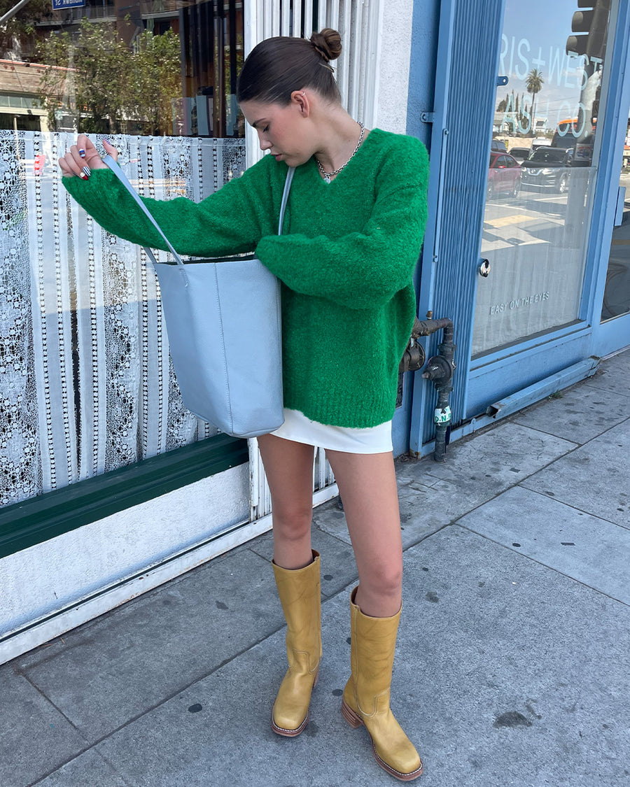 front view of model wearing green textured v-neck sweater and twill skirt