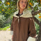 up close of model wearing brown oversized trench coat with white and dainty blue folk print tie shawl, arm and hem trim