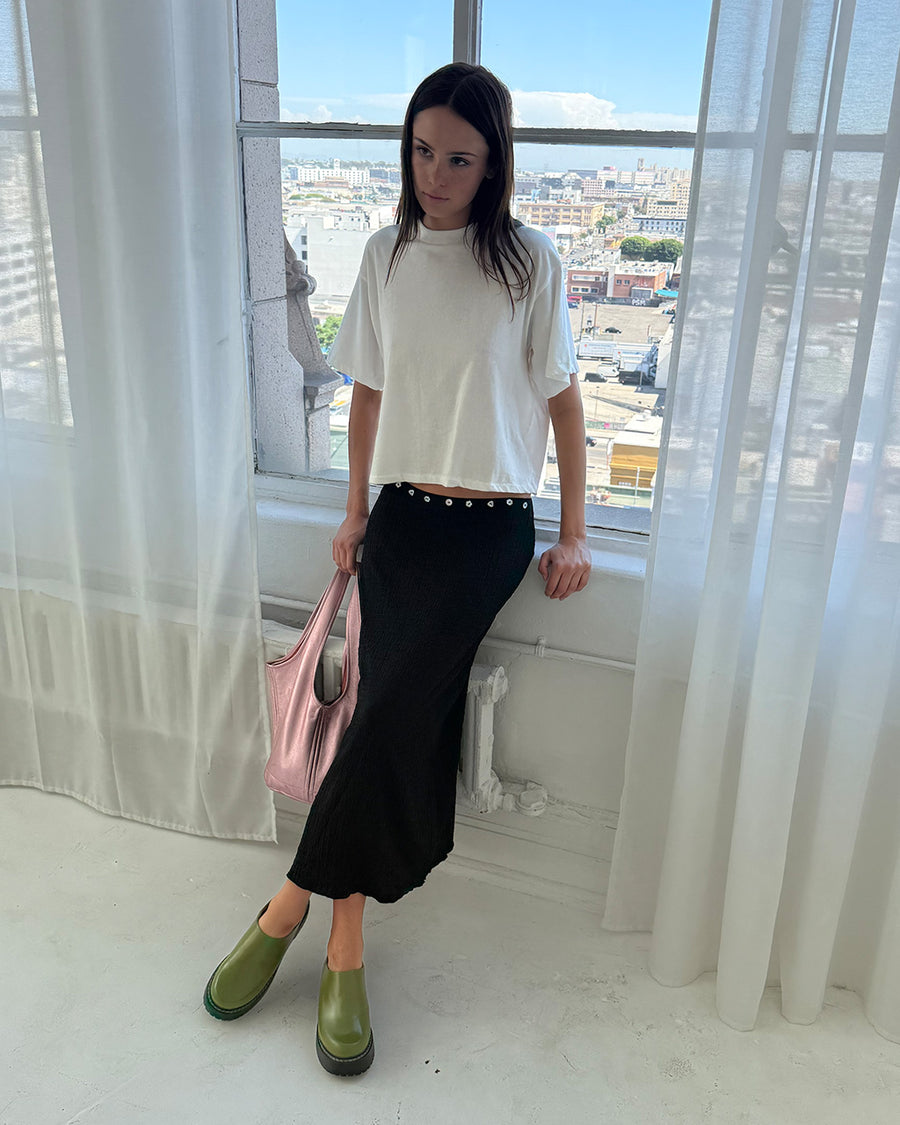 model wearing black crinkle midi skirt with shaped shell buttons on the top