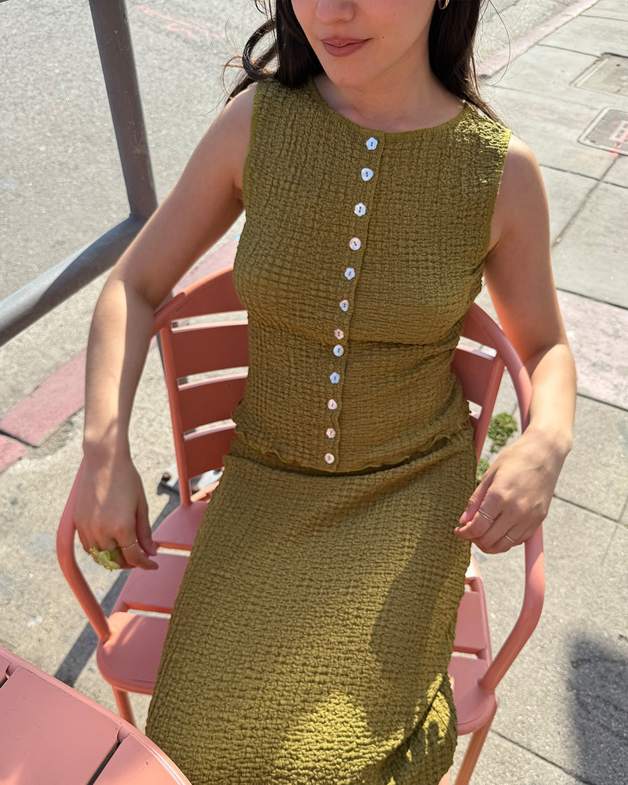 model wearing olive crinkle midi skirt with shaped shell buttons on the top and matching tank