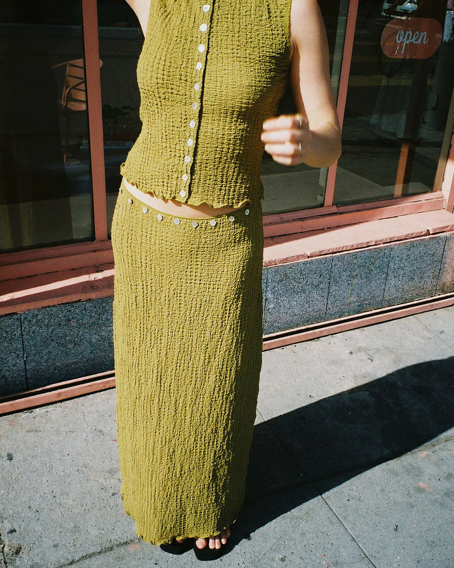 model wearing olive crinkle midi skirt with shaped shell buttons on the top and matching tank
