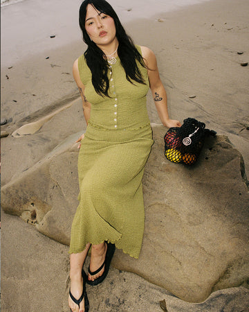 model wearing olive crinkle midi skirt with shaped shell buttons on the top and matching tank
